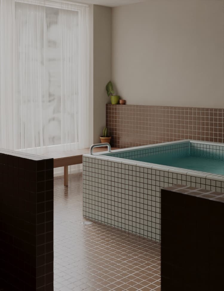 Tiled hot bath beside a curtained window